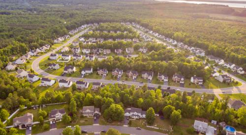 aerial view of housing subdivision surrounded by trees and green space