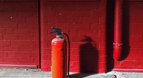 Fire extinguisher on floor against red wall