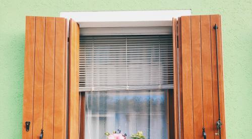House exterior of window with wooden shutters and potted plant