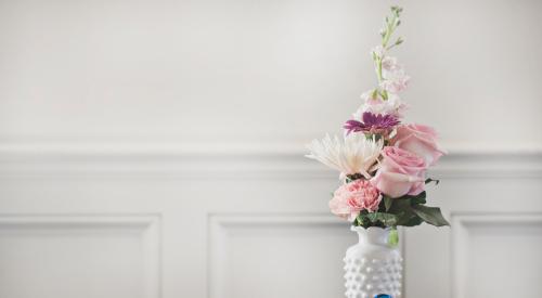 Bouquet of flowers in vase on table with blue bird