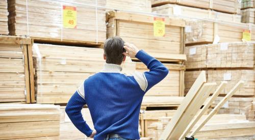 confused man looking at stacked lumber