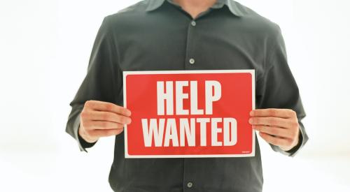 Man holding help-wanted sign as labor shortage looms for builders