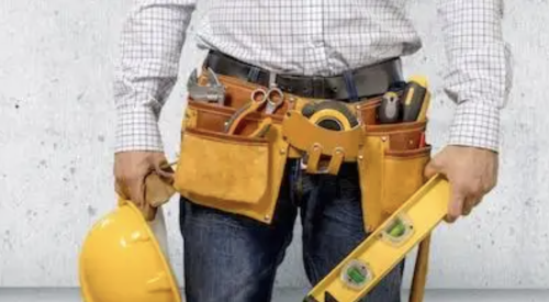 man wearing toolbelt and holding a hard hat and level
