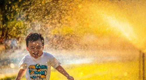 Boy running through sprinkler