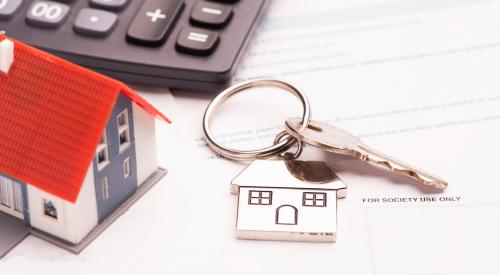 Mortgage application and house keys next to calculator