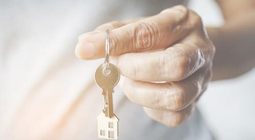 Baby Boomer's hand holding brass-colored house key