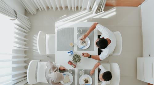 Overhead shot of family at kitchen table eating breakfast