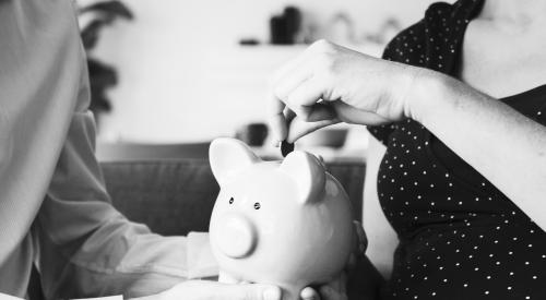 Black and white photo of couple putting money in piggy bank