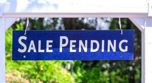 Blue and white 'sale pending' sign in residential yard