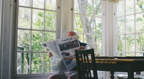 Elderly man reading newspaper