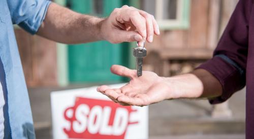 Person accepting house keys in front of new home sold