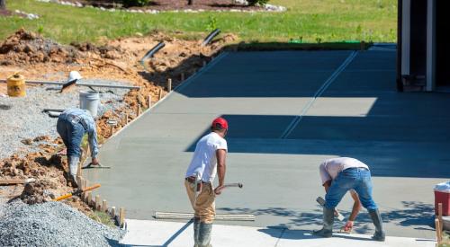 Workers spreading concrete on construction site