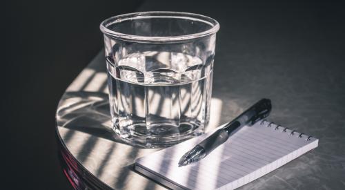 Glass of water and pad with pen on table