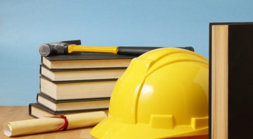 Yellow hard hat next to a diploma and stack of books
