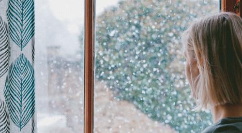 Woman looking out window at snow