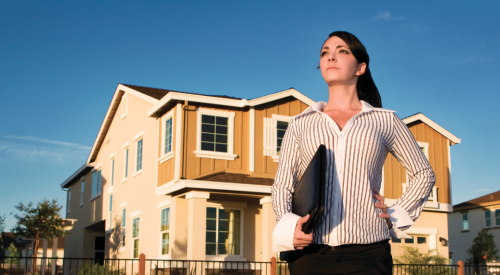 Successful home salesperson standing in front of a new home