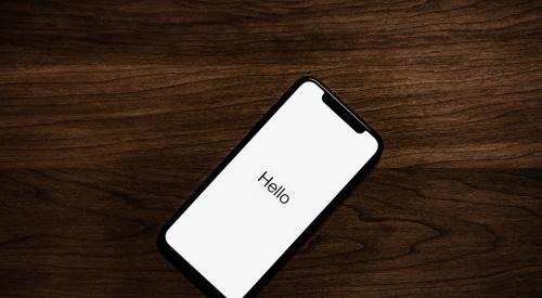 iPhone on table screen reads 'Hello'