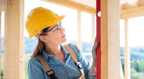 Women with hard hat and carpeter's level