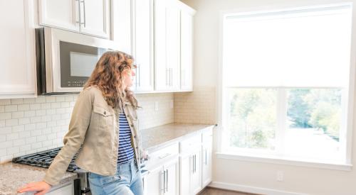 Female homebuyer standing in modern kitchen looking out window