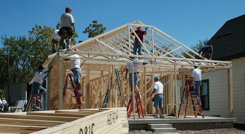 Construction crew framing new house with timber